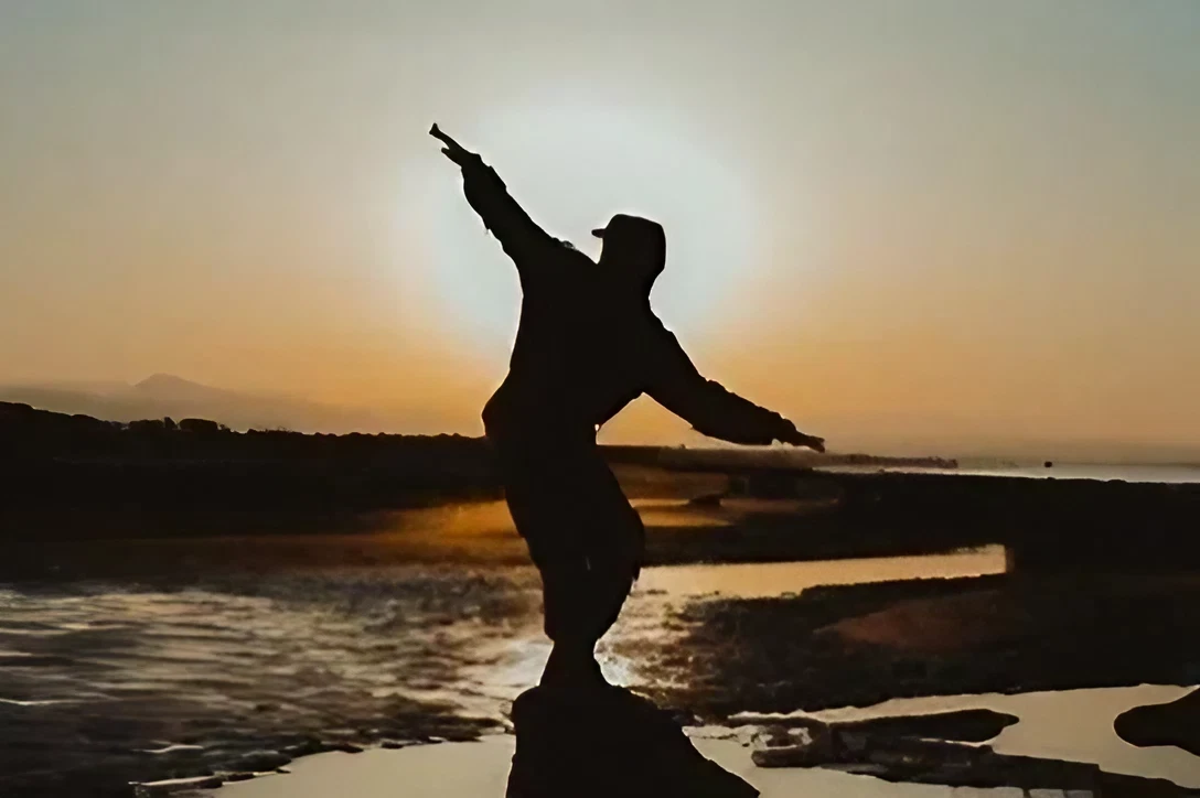 Silhouette of person balancing at sunset beach.