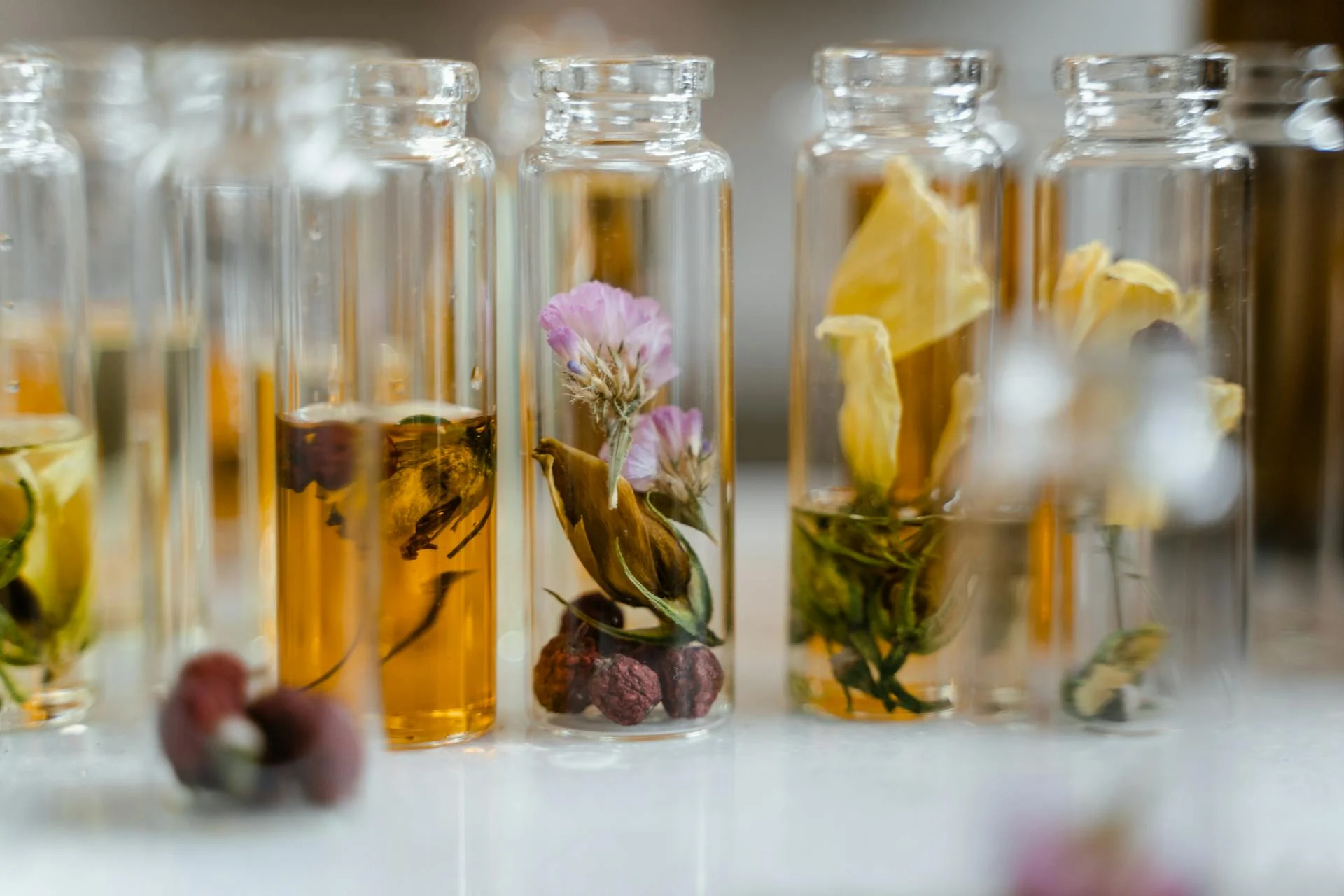 Glass vials with flowers and herbs inside.